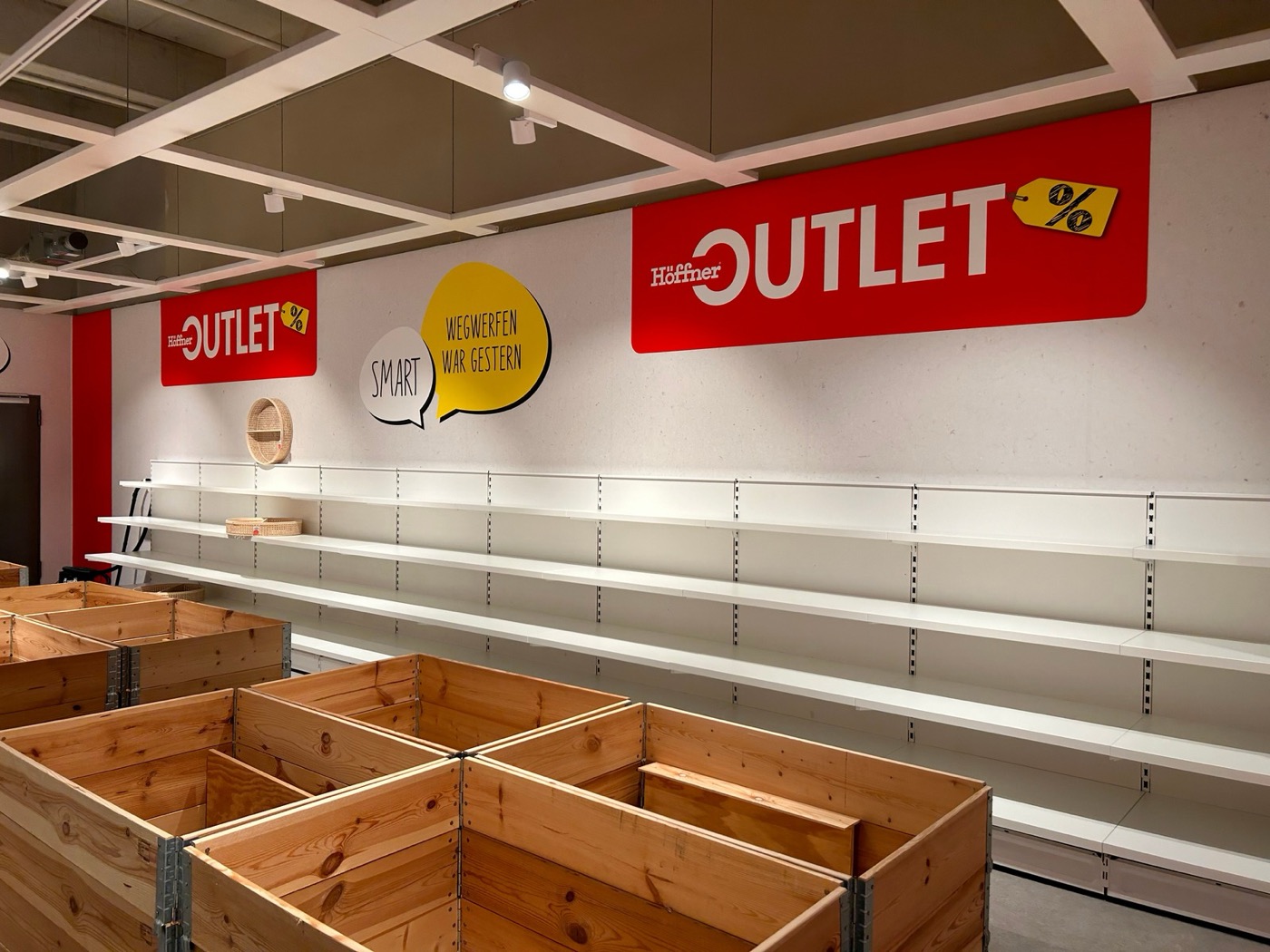 Rote Wandbeklebung mit Outlet-Schriftzug über Regalen